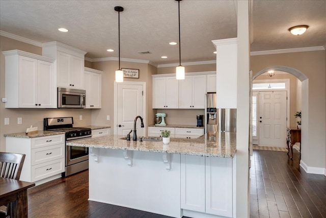 kitchen featuring arched walkways, stainless steel appliances, dark wood-type flooring, a sink, and white cabinetry