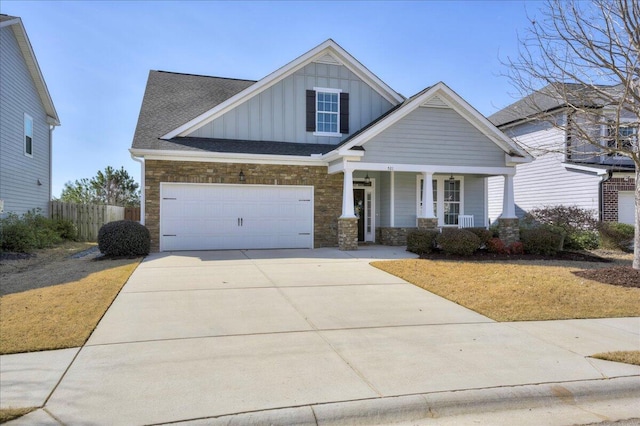 craftsman house with driveway, a garage, covered porch, fence, and board and batten siding