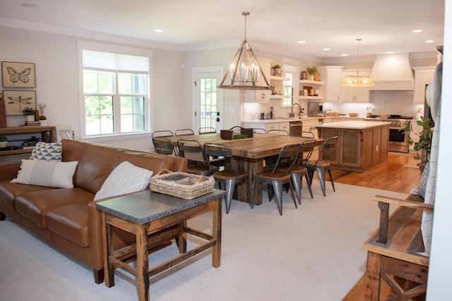 dining space with ornamental molding, sink, and light wood-type flooring