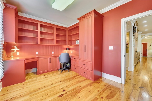 unfurnished office featuring ornamental molding, built in desk, and light wood-type flooring