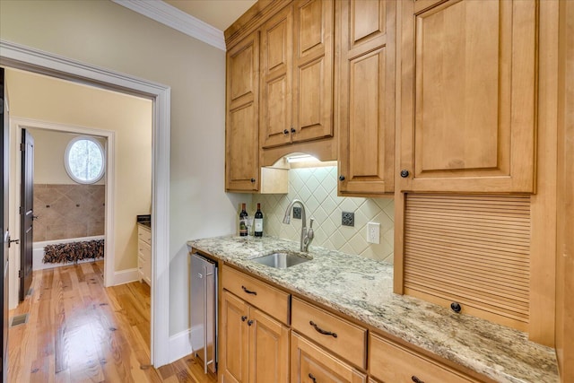 kitchen featuring decorative backsplash, crown molding, light hardwood / wood-style flooring, light stone counters, and sink