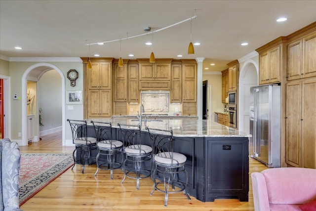 kitchen with a spacious island, light stone countertops, a kitchen bar, stainless steel appliances, and crown molding