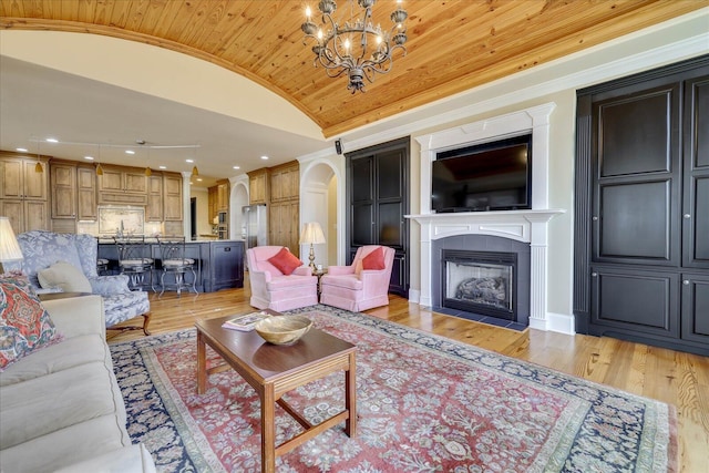 living room with crown molding, light hardwood / wood-style flooring, lofted ceiling, and a notable chandelier