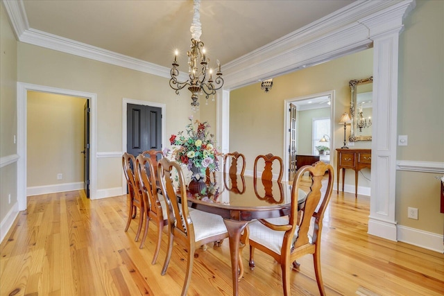 dining space with light wood-type flooring, ornamental molding, and a notable chandelier