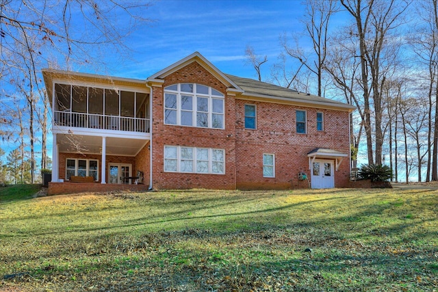 rear view of house featuring a yard and a sunroom