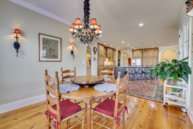 dining space with crown molding, an inviting chandelier, and light hardwood / wood-style flooring