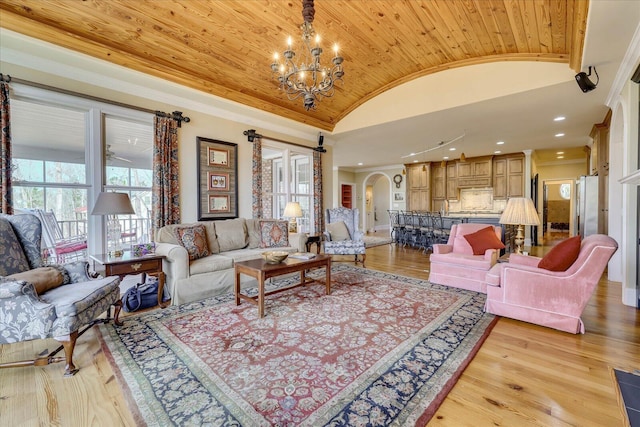 living room featuring lofted ceiling, light hardwood / wood-style flooring, ornamental molding, a chandelier, and wooden ceiling