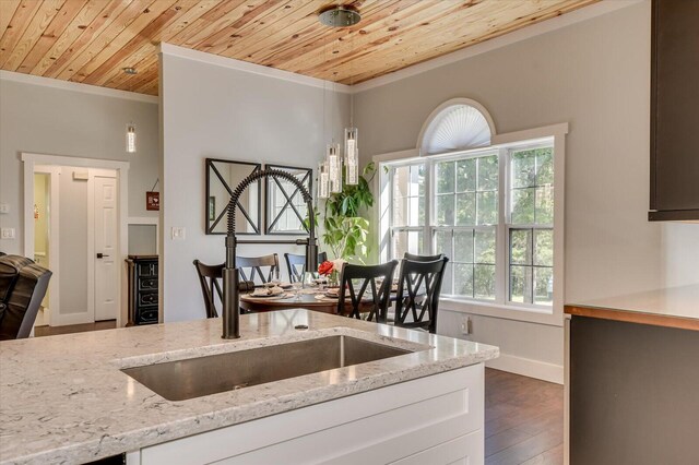 kitchen with light stone countertops, dark wood-type flooring, wood ceiling, and ornamental molding