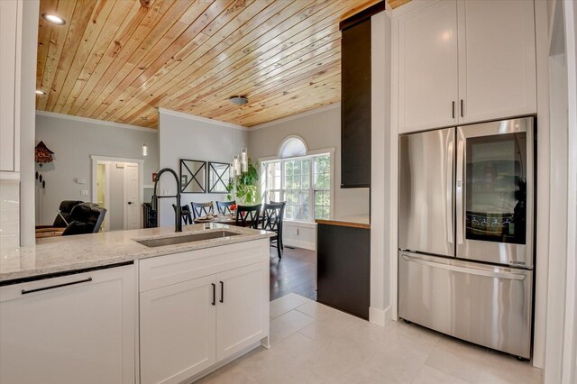 kitchen with light stone countertops, dishwasher, built in fridge, white cabinets, and ornamental molding