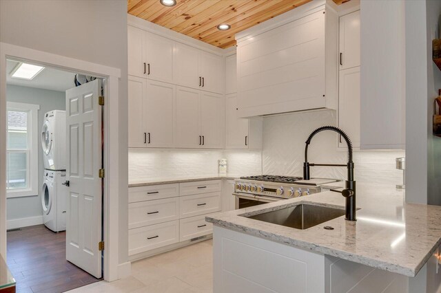 kitchen featuring kitchen peninsula, light stone counters, wooden ceiling, and stacked washer / drying machine