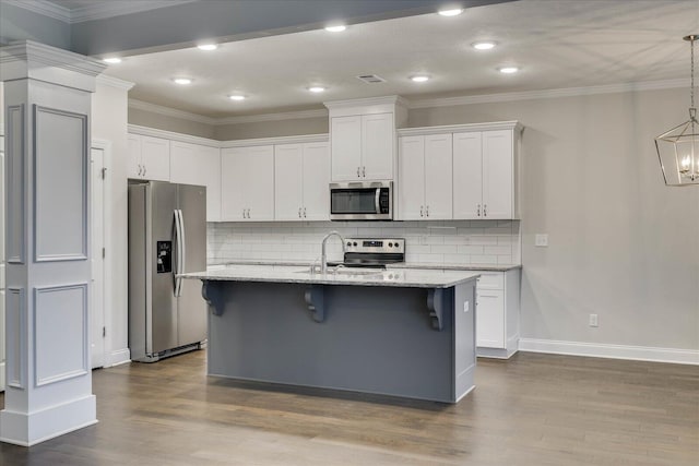 kitchen with a kitchen bar, a center island with sink, stainless steel appliances, light stone countertops, and white cabinets