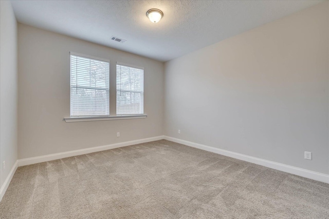 carpeted empty room featuring a textured ceiling