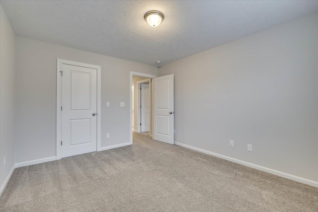 unfurnished room featuring light colored carpet and a textured ceiling