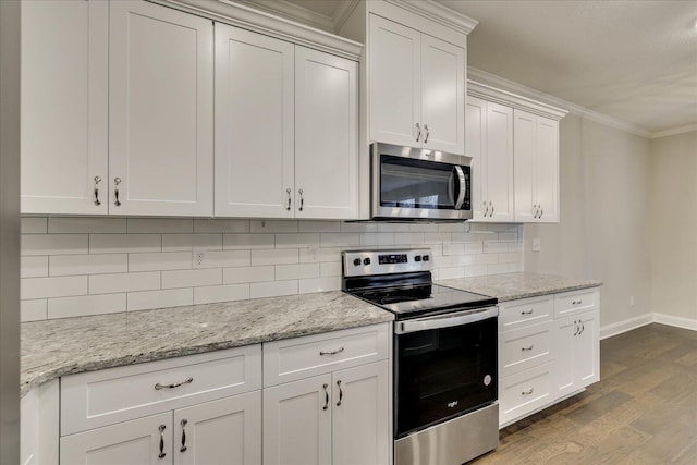 kitchen featuring white cabinetry, appliances with stainless steel finishes, light stone countertops, hardwood / wood-style floors, and decorative backsplash