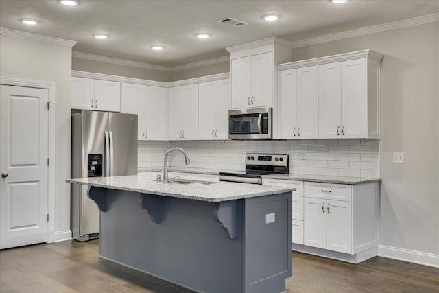 kitchen with white cabinetry, stainless steel appliances, a kitchen island with sink, and a breakfast bar area