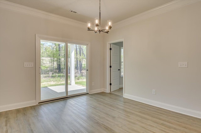 spare room featuring a chandelier, light wood-type flooring, and ornamental molding