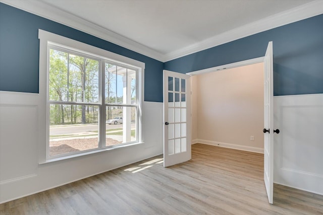 empty room featuring light hardwood / wood-style floors, crown molding, and french doors