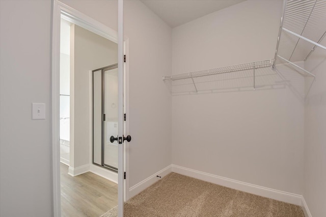 walk in closet with light hardwood / wood-style floors