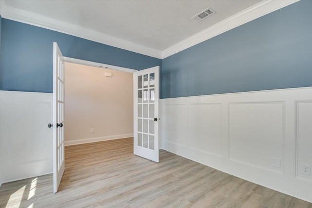 empty room featuring light hardwood / wood-style flooring, french doors, and ornamental molding