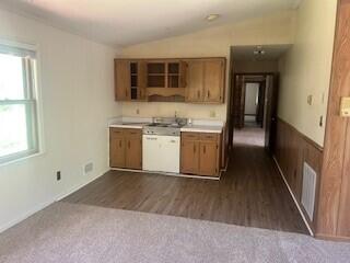 4521 Zola Dr, Evans, GA 30809 - kitchen featuring brown cabinetry, vaulted ceiling, light countertops, dark colored carpet, and dark wood-style flooring
