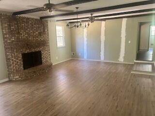 4521 Zola Dr, Evans, GA 30809 - unfurnished living room with wood finished floors, a fireplace, a chandelier, a ceiling fan, and beamed ceiling