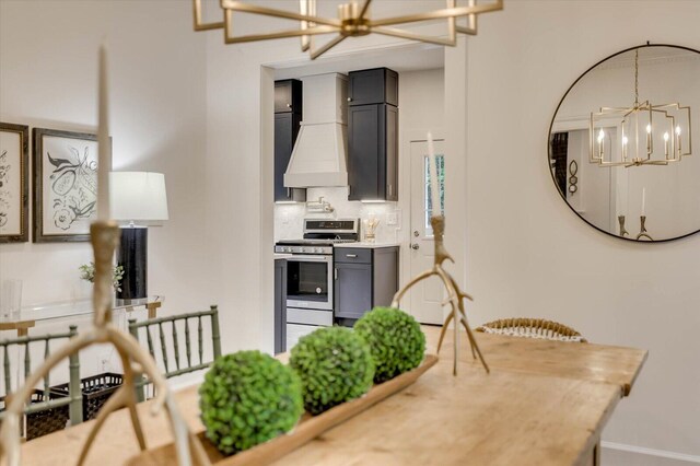 kitchen with gray cabinetry, stainless steel range oven, backsplash, a chandelier, and custom exhaust hood