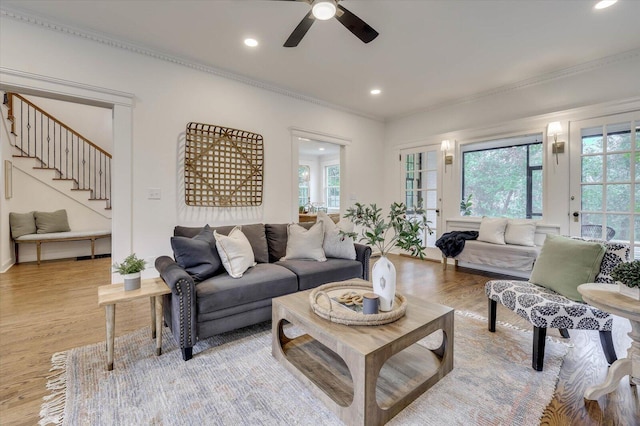 living room with light hardwood / wood-style flooring, ceiling fan, and ornamental molding