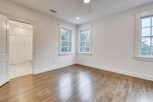 unfurnished bedroom featuring hardwood / wood-style floors, ensuite bath, ceiling fan, a spacious closet, and a closet