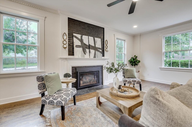 living room with wood-type flooring, a brick fireplace, a wealth of natural light, and crown molding