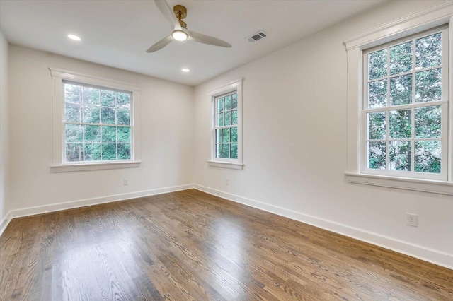 spare room with dark hardwood / wood-style flooring, ceiling fan, and plenty of natural light