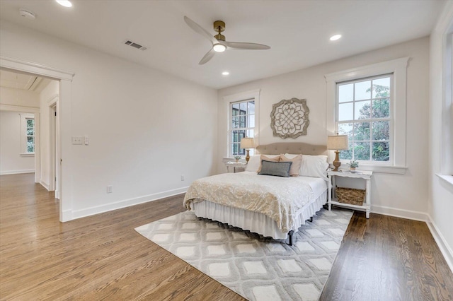 bedroom with multiple windows, ceiling fan, and wood-type flooring