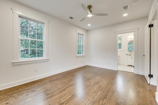 empty room featuring a wealth of natural light, ceiling fan, and hardwood / wood-style flooring