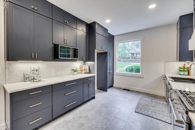 kitchen featuring backsplash, sink, and high end stainless steel range oven