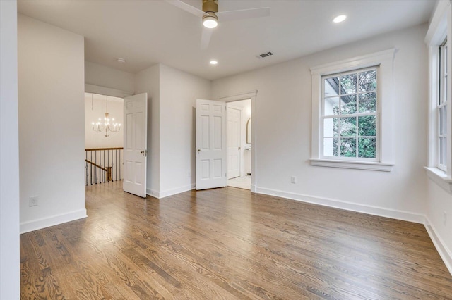 unfurnished bedroom with dark wood-type flooring and ceiling fan with notable chandelier