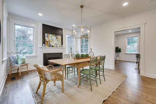 dining area featuring hardwood / wood-style flooring, a brick fireplace, and a healthy amount of sunlight