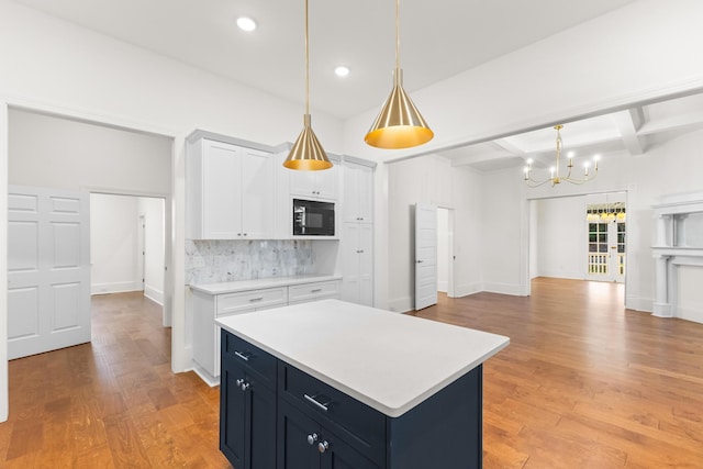 kitchen featuring black microwave, white cabinetry, a center island, beamed ceiling, and backsplash