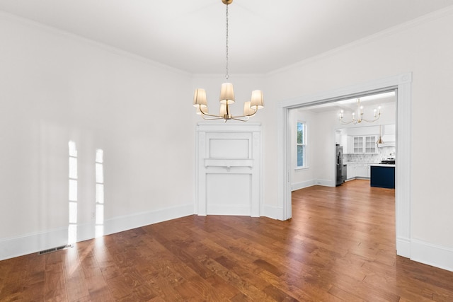 unfurnished dining area featuring hardwood / wood-style flooring, ornamental molding, and a notable chandelier