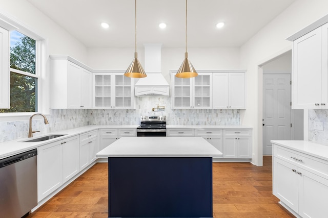 kitchen featuring stainless steel appliances, sink, decorative light fixtures, white cabinets, and a center island