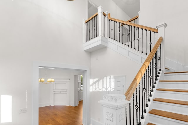 stairs featuring hardwood / wood-style floors, a notable chandelier, and a towering ceiling