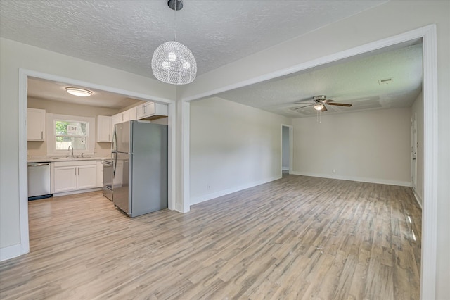 2001 Hiram Rd, Augusta, GA 30904 - kitchen with stainless steel appliances, a textured ceiling, white cabinetry, light wood finished floors, and light countertops