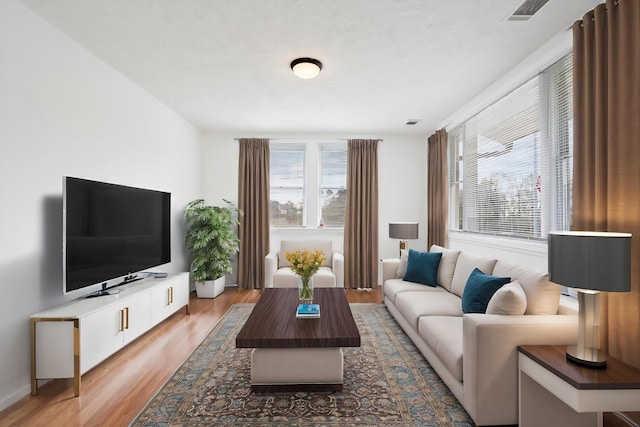 living area with visible vents, wood finished floors, and a wealth of natural light