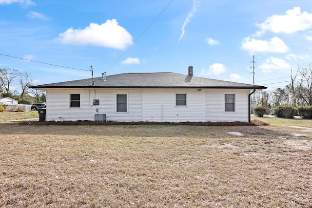 rear view of property featuring roof with shingles, a lawn, and central air condition unit