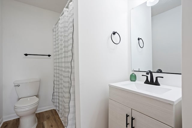 bathroom featuring baseboards, vanity, toilet, and wood finished floors