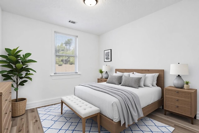 bedroom with light wood-style flooring, visible vents, and baseboards