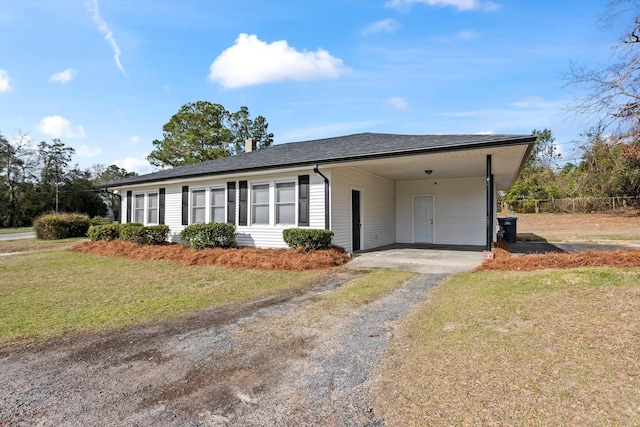 ranch-style home with driveway, a shingled roof, a carport, and a front yard