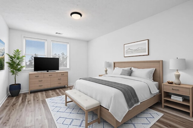 bedroom with wood finished floors, visible vents, and baseboards