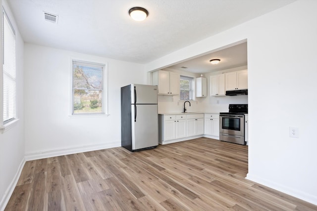 kitchen with white cabinets, stainless steel electric range oven, freestanding refrigerator, light countertops, and under cabinet range hood