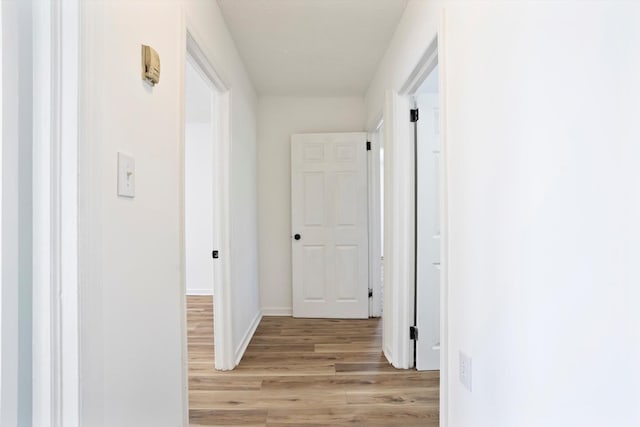 hallway featuring baseboards and light wood-style floors