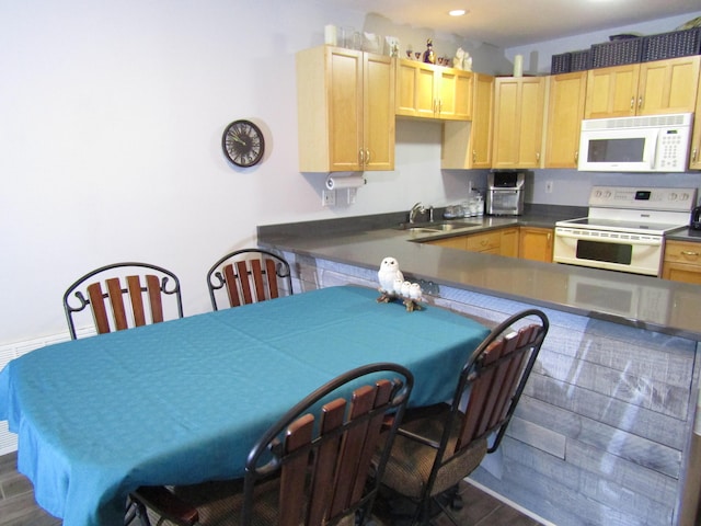 kitchen featuring light brown cabinetry, sink, white appliances, and kitchen peninsula