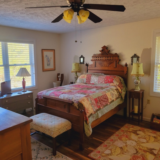 bedroom with a ceiling fan, wood finished floors, baseboards, and a textured ceiling